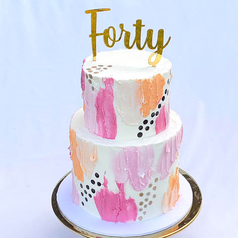 Simple script cake topper on a pink, orange and white cake.