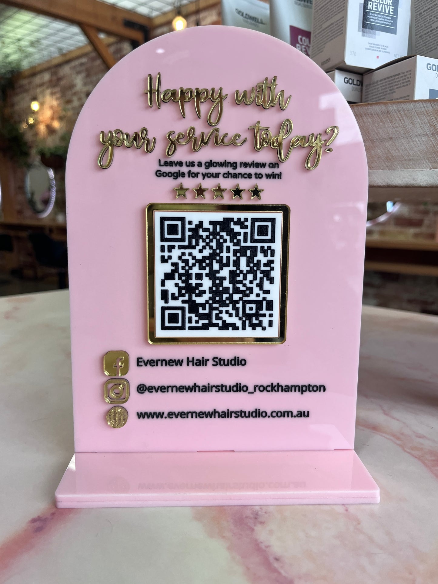 Pink sign with QR code and text on a marble surface